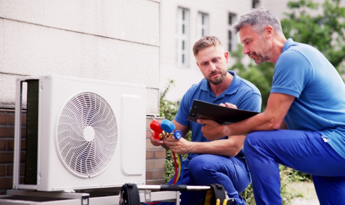 HVAC technicians reviewing an outdoor air conditioning unit in Windsor, CO